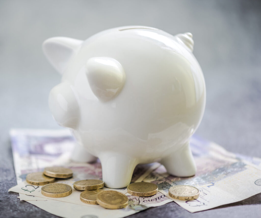 A piggy bank on a pile of British money representing someone's pension savings