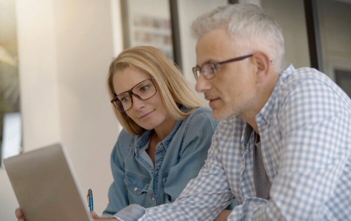 A middle-aged couple are looking at their laptop, researching information about their UK and NZ state pensions. (c) Adobe Stock