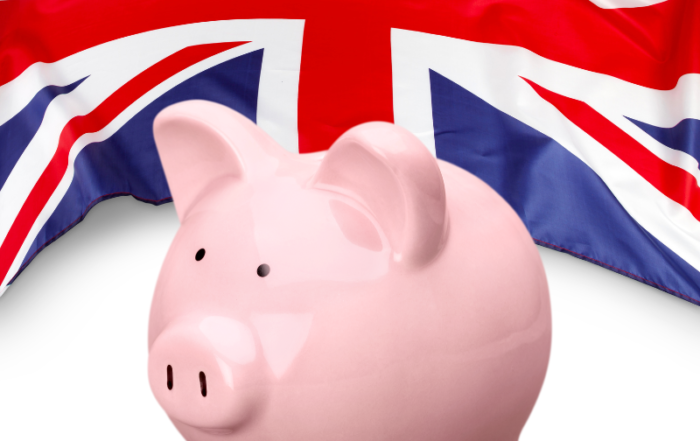 A pink piggy bank sits in front of a Union Jack. Image created in Canva.