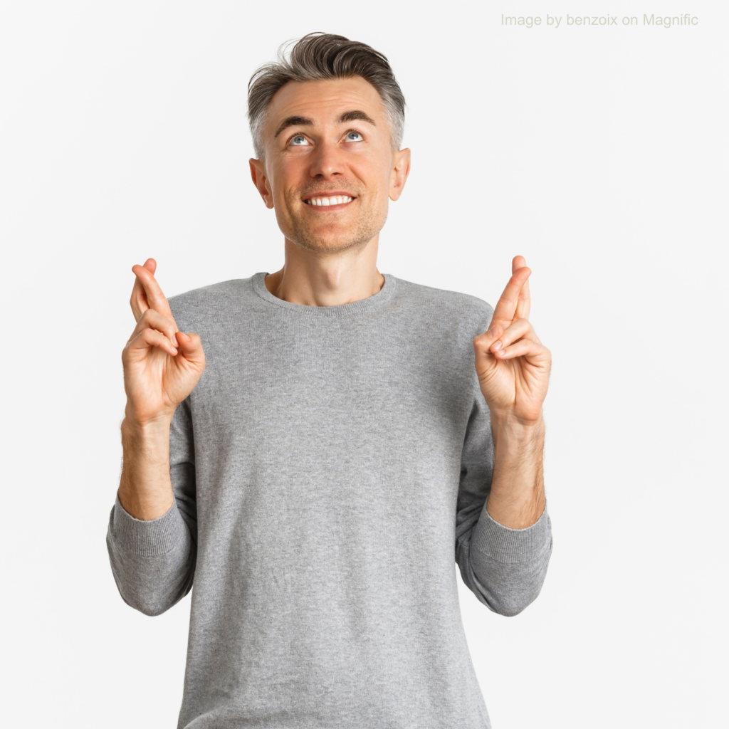 A man has his fingers crossed, looking hopeful – Image by benzoix on Magnific A man in his forties wearing a grey long-sleeved shirt has his fingers crossed. He is looking upwards, as if hopeful that good news is on the way.